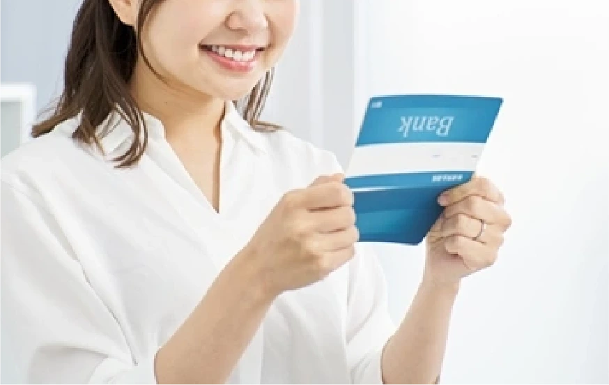 銀行通帳を見て笑顔になる女性